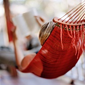 Young woman reading in hammock on terrace