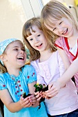Three girls holding plants with root balls in their hands