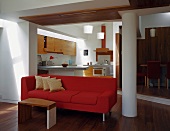 Side table in front of red sofa with open-plan kitchen in background