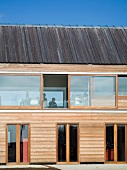 Ausschnitt eines Wohnhauses mit Holzfassade und Fensterband mit Glasschiebeelementen