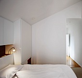White, attic bedroom with open doorway and view into corridor beyond