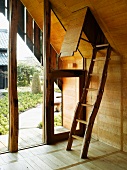 Rustic ladder leading to open hatch in wood-panelled room
