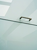 Bracket handle on white cupboard door with frosted glass surface