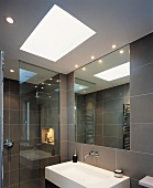 Modernes, grau gefliestes Badezimmer mit Oberlicht über dem Designer-Waschbecken