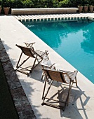 Sunbathing by the pool - wooden deckchairs with folding side tables