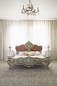 Rococo-style double bed in front of closed curtains in bedroom