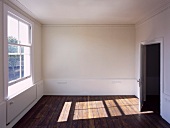 Pattern of light on dark wood floorboards in empty room