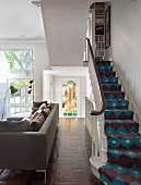 Leather sofa next to staircase with 60s-style patterned runner