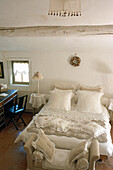 Schlafzimmer mit weißer Bettwäsche und traditionellen Dekoelementen