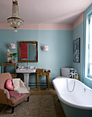 Bathroom in pastel colours with free-standing bathtub and chandelier