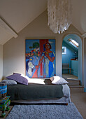 Sloping ceiling bedroom with artwork and large ceiling lamp