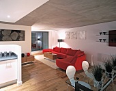 Offener Wohnraum mit Essplatz und roter geschwungener Couch