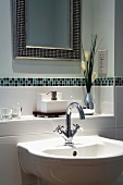 Sink below tiled shelf with border and framed mirror