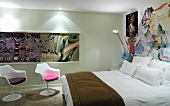 Künstlerisch ausgestaltetes Hotelzimmer mit weissen Schalensesseln im Retro-Stil