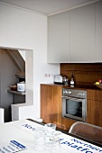 Modern kitchen unit in fine wood with white suspended cupboards and table top with printed underground map