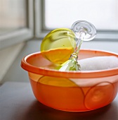 Colored stemware being washed in an orange plastic bowl