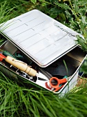 Metal tin with garden tools in the grass