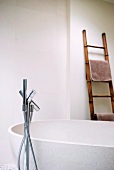 Bathroom with free-standing bathtub, floor-mounted tap fittings and ladder as towel rack