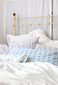 Country-house-style pillows against metal frame of old bed