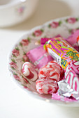 Red and white marbled sweets and sweet packaging on a nostalgic floral-patterned plate