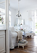 View into romantic living room with seating upholstered in white and rustic wooden floor