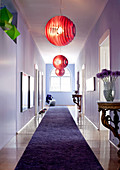 Three red Foscarini pendant lamps and antique console tables in lilac, eclectic ambiance of long period hallway