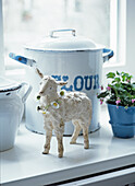 Decorative lamb with daisy chain and enamel pots on a windowsill