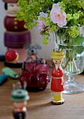 Knitting dollies and antique toys next to vase of flowers