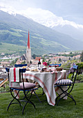 Set table in garden with view of the town of Schlander, church tower and mountain range