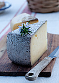 Ein Stück Südtiroler Käse mit Messer auf Holzbrett