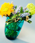 Blumenstrauss mit gelben und violetten Blumen in Glasvase