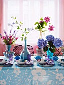 Gedecke mit gemusterten Schalen und Blumensträussen auf Tisch