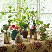 Flowers and sprigs in assorted vases on a table with a retro tablecloth