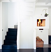 Open fireplace with a fire in a lobby and view of black stairs