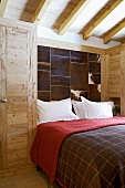 Modern bedroom with rustic wooden wardrobe and panels of animal skin on wall