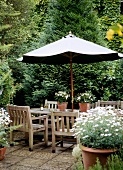 Dining area on terrace with wooden chairs beneath parasol