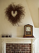 Heart-shaped wicker wreath on wall and antique clock on mantelpiece