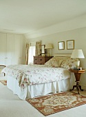Traditional bedroom with floral throw on bed and Biedermeier-style bedside table