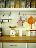 Vintage-style kitchen utensils hanging from stainless steel rail below shelf with storage jars