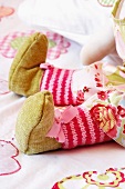 Legs of a hand-made rag doll with pink striped stockings and shoes tied with bows