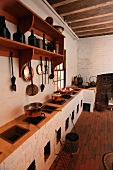 Rustic kitchen with multiple hearths in masonry counter and copper kitchen utensils