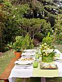 A table laid in a garden with table decoration and appetizers