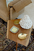 Verschiedene Schalen auf schlichtem Beistelltisch aus Holz im Fiftiesstil und teilweise sichtbares Sofa mit Armlehne