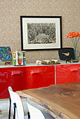 Ausschnitt eines Tisches aus Massivholz vor Sideboard mit rot lackierten Türfronten