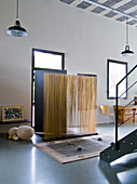 Künstlerisch gestalteter Windfang aus Holzstäben vor Haustür in loftartigem Wohnraum