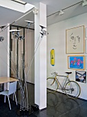 Multi-armed standard lamp next to seating area in open-plan hallway with bicycle parked on glossy black tiled floor