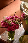 A bouquet of ranunculus reflected in a silver vase