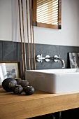 White countertop washbasin on wooden washstand decorated with small, anthracite-coloured ceramic vases