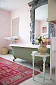 Cozy bathroom in 'Shabby Style' with colorful carpet and imposing mirror above an antique bathtub