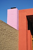 Violett und rot verputzte Fassadenflächen und grau geschlemmte Backsteinmauer